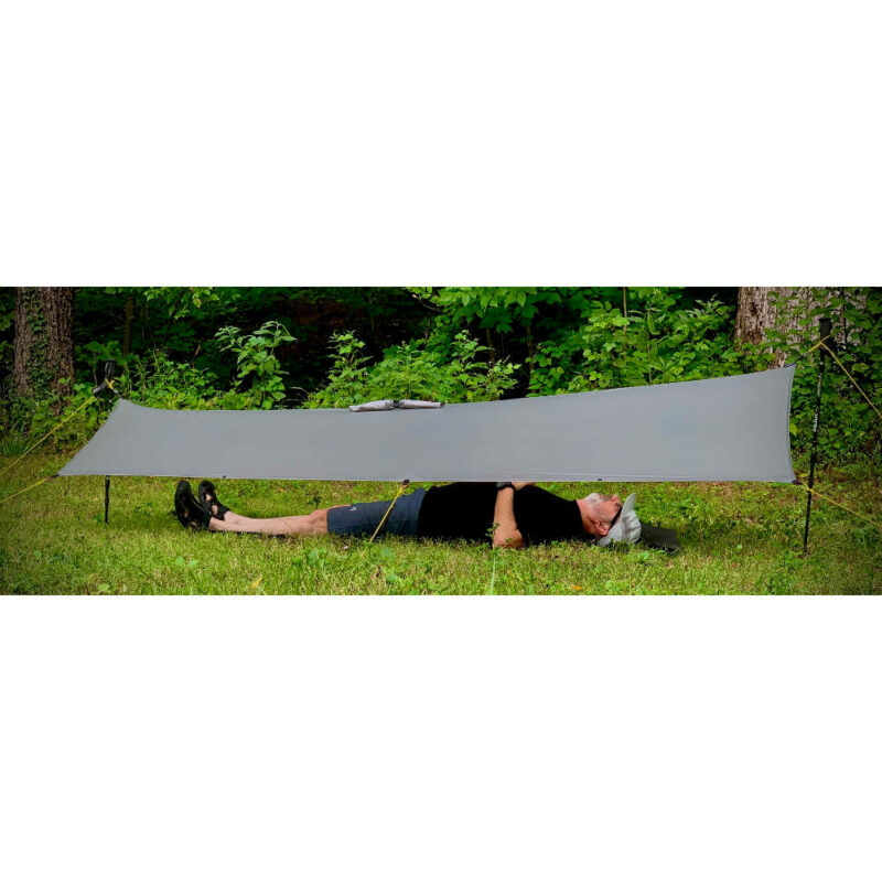 The MLD Pro Poncho used as a shelter. The model lying beneath the shelter is over 6ft tall and there is plenty of tarp on either side of him.