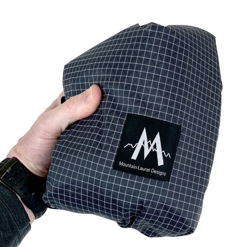 An MLD Core backpack folded and held in a man's hand.