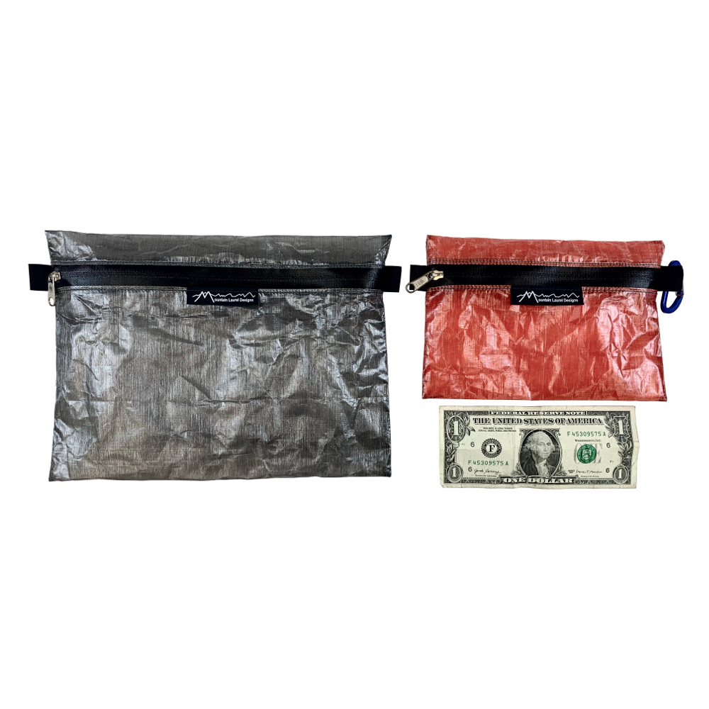 An MLD Zip Pouch Size Comparison. A large grey pouch on the left, with a small red pouch and a $1 US bill on the right.