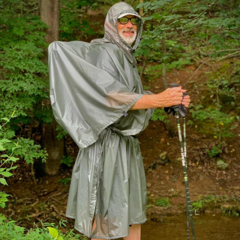 A side view of the MLD Pro Poncho in Poncho Mode on an ultralight hiker. His UL pack fits under the poncho.