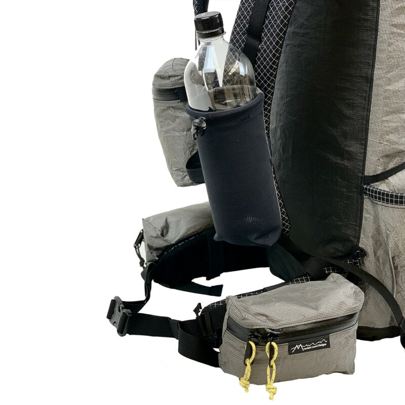 A 3/4 side view of the MLD Shoulder Pockets on a backpack. The zippered pocket is on the right strap (background), and the water bottle holder is on the left (foreground). They connect to the daisy chains.