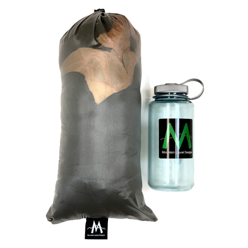 The Vision Quilt packed in its stuff sack next to a Nalgene bottle for a size comparison. It is maybe twice as long and twice as wide.