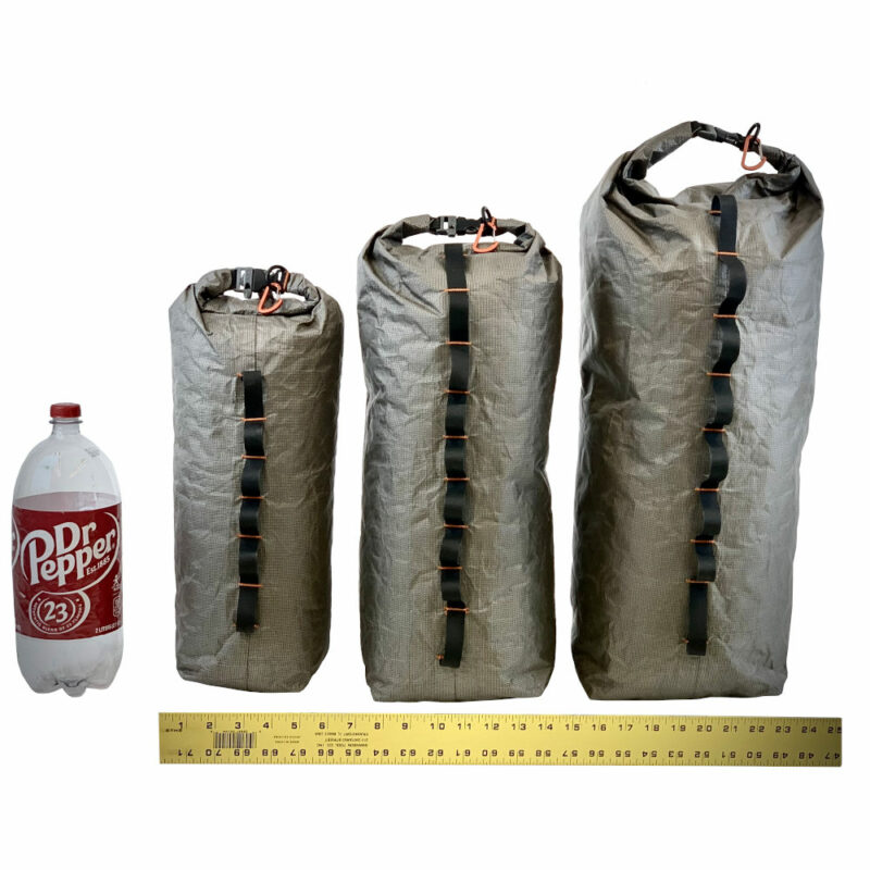 A 2L soda bottle sits next to 7L, 12L, and 22L Ultra X 200 Bike Dry Bags. There is a measuring tape along the bottom showing the approx. widths.