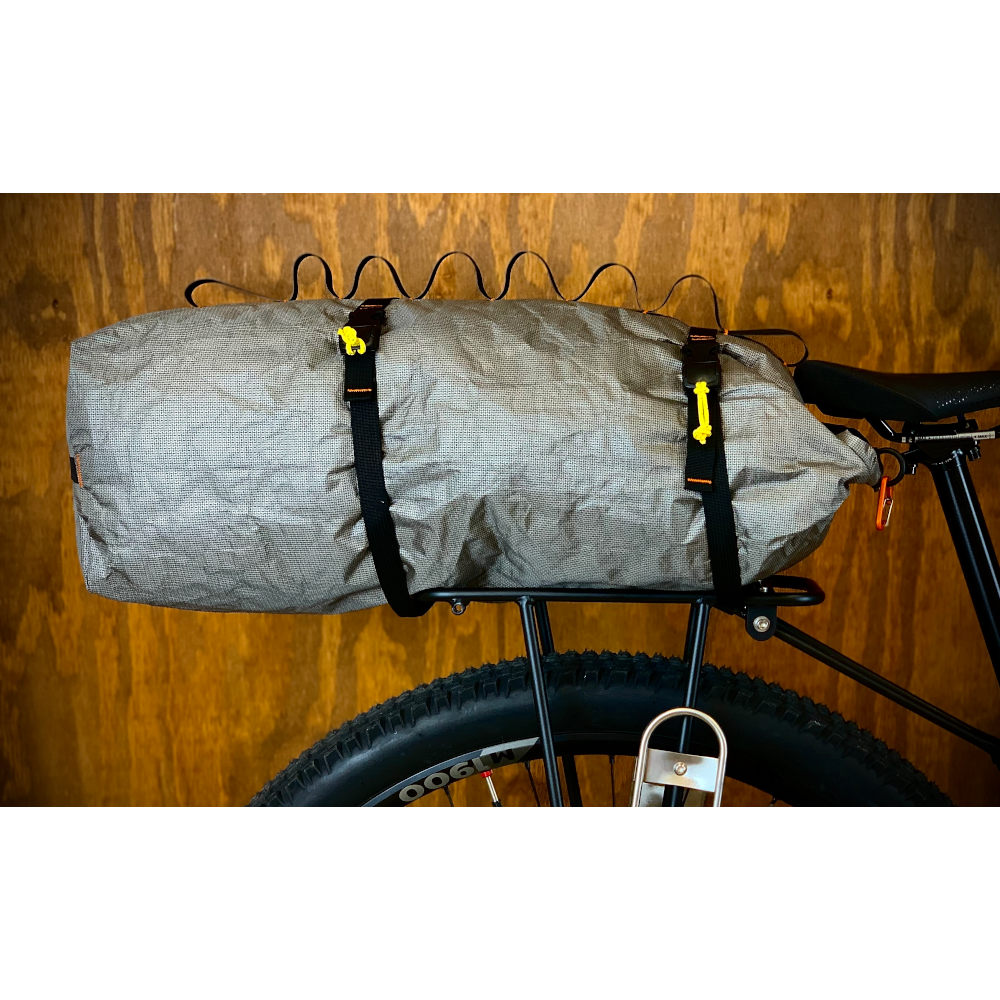 A set of bikepacking straps secures an ULTRA 200X Dry back to the back roack of a bike.