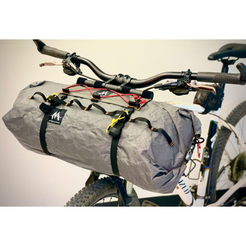 A 3/4 side view of a Border Handlebar Harness System mounted on a bike and holding and Ultra X Double End Handlebar Dry Bags