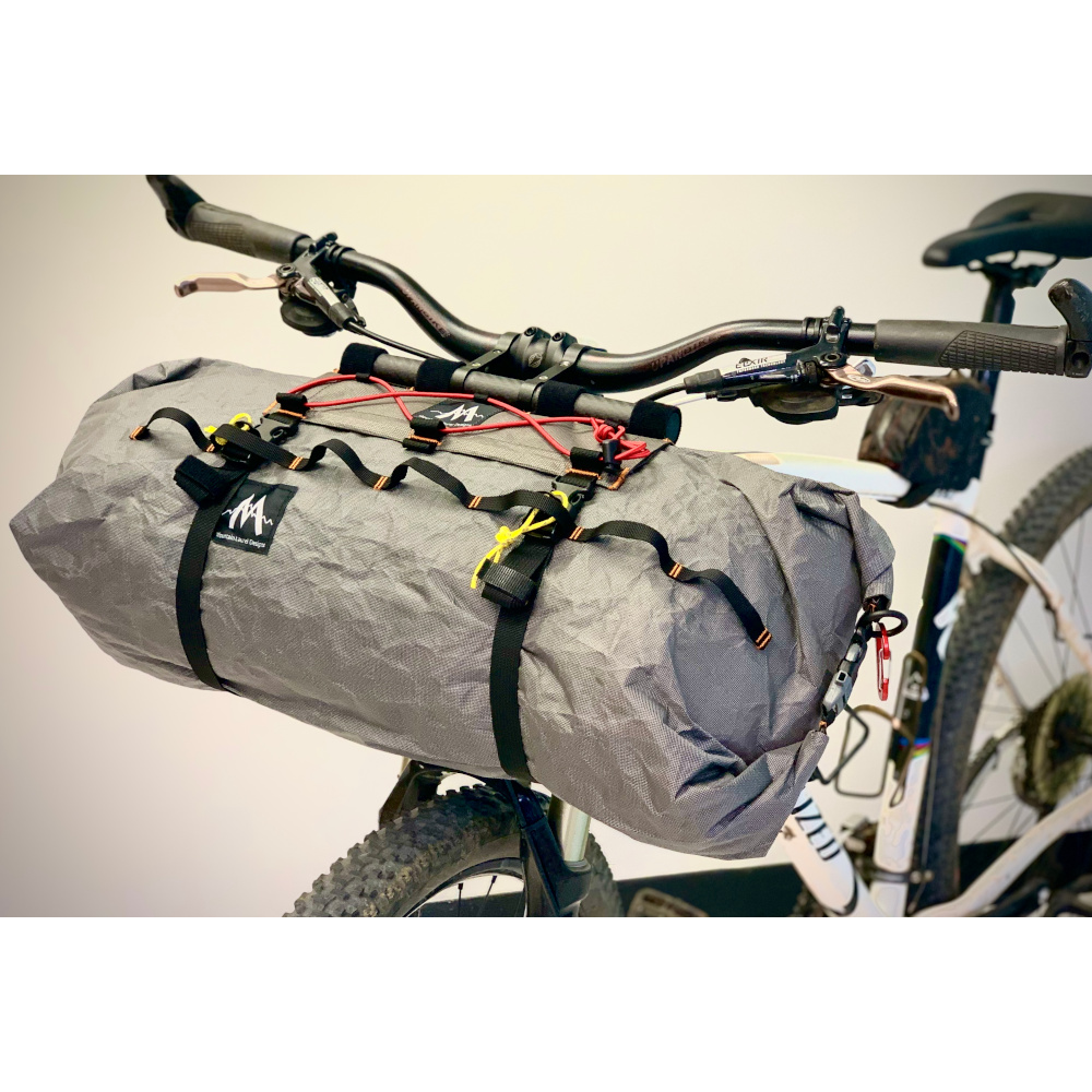 A 3/4 side view of a Border Handlebar Harness System mounted on a bike and holding and Ultra X Double End Handlebar Dry Bags