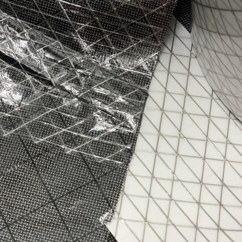 A piece of Ultra TNT Repair + Seal Seam Tape being used to repair technical fabric