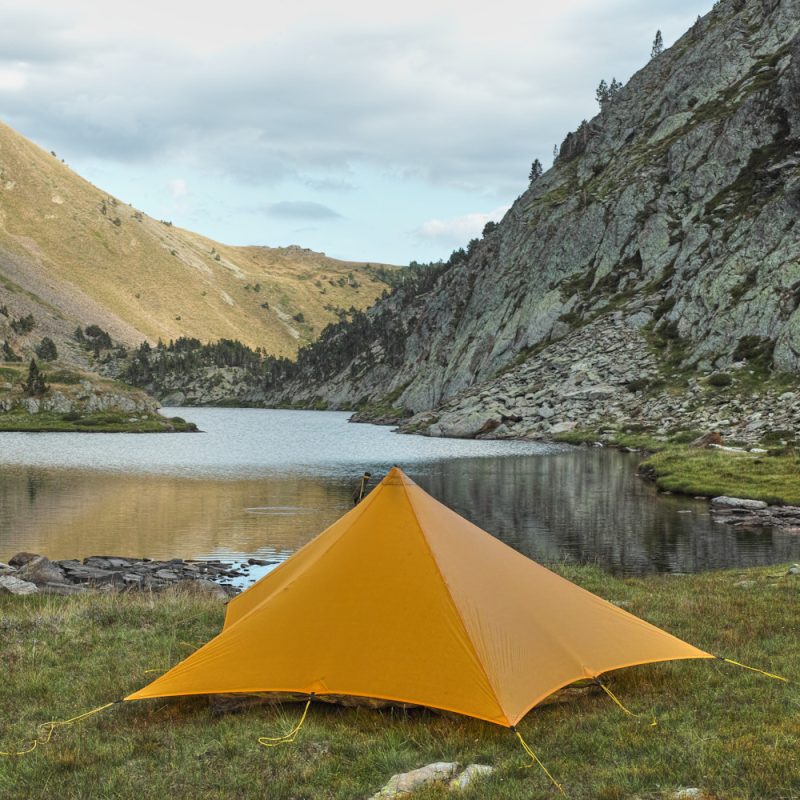AThe back view of a citrus yellow LittleStar Pitched set up next to an alpine lake.