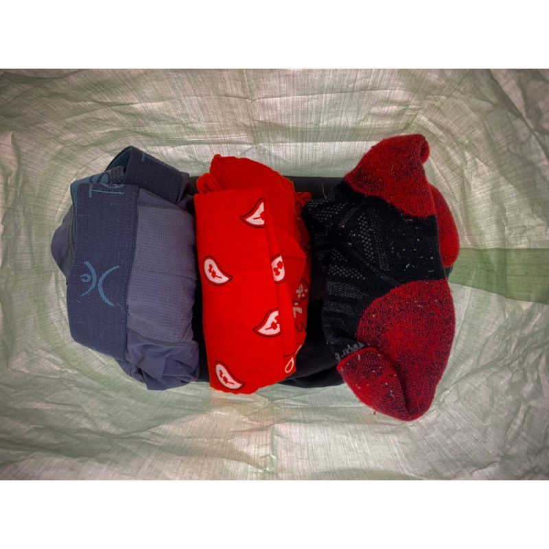MLD Roll Top Ultralight Packing Cube internal view. There is a pair of undies, a bandana, and socks ontop of a pair of pants.