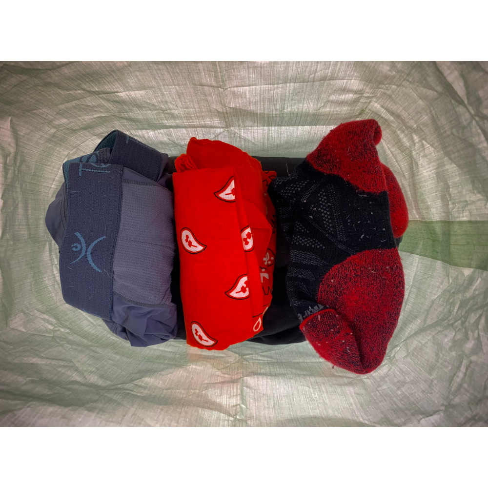 MLD Roll Top Ultralight Packing Cube internal view. There is a pair of undies, a bandana, and socks ontop of a pair of pants.